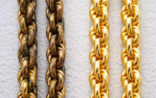 Close up of a heavily tarnished gold plated chain next to a new one.